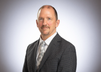 Joe Dunford is wearing a dark suit and light gray tie against a white background